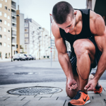 Close up of. a runner kneeling down to tie his shoe