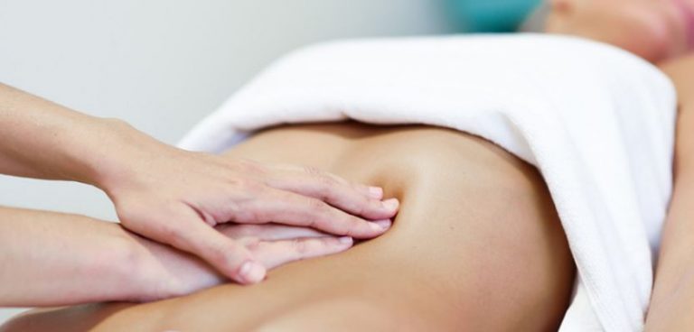 close up of hands giving postpartum massage focused on the small of the back