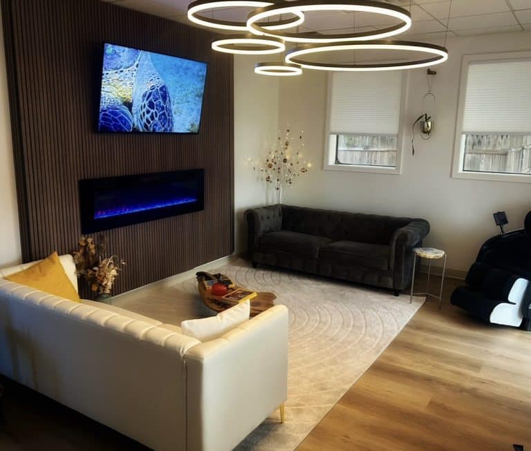 Waiting lounge at Luminous You Massage with two couches and lighting display of five circular rings of different sizes hanging from ceiling