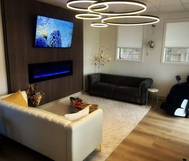 Waiting lounge at Luminous You Massage with two couches and lighting display of five circular rings of different sizes hanging from ceiling