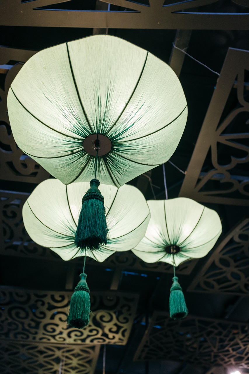 soft green set of Chinese lanterns with dark green tassels hanging from a ceiling