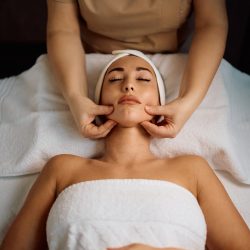 woman in a white towel cover receiving TMJ massage therapy